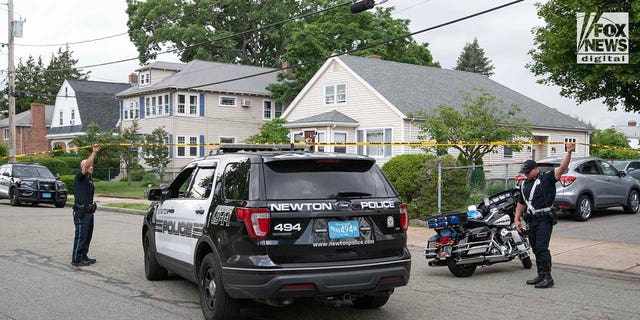 Police officers gather outside of the home where a triple homicide occurred in Newton, Massachusetts