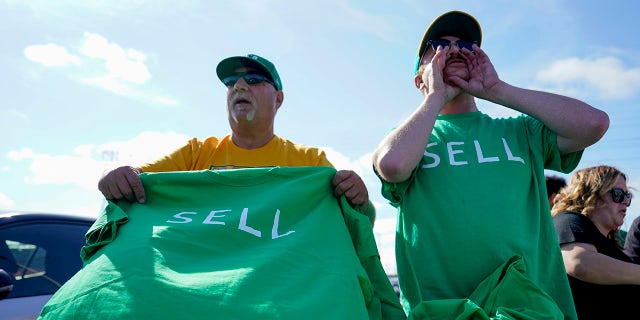 A los fanáticos sostienen camisetas que dicen "VENDER"