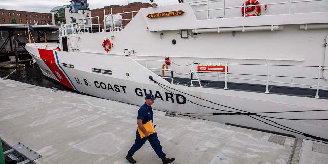 A member of the Coast Guard walks by a Coast Guard Cutter at the US Coast Guard Base Boston