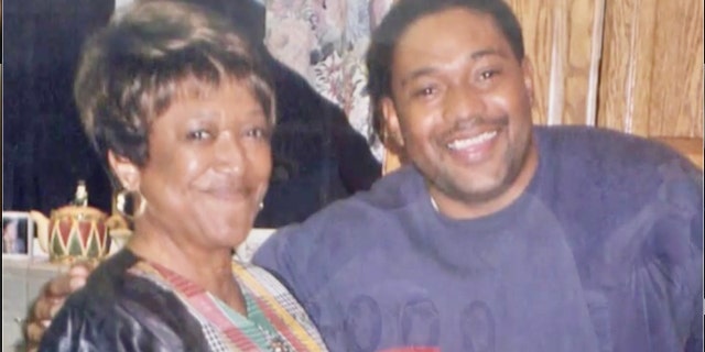 Minnie Smith smiling next to her son wearing a purple sweater