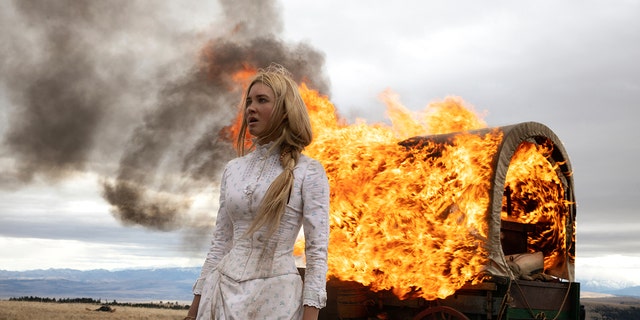 Isabel May wearing a prairie dress next to a fire