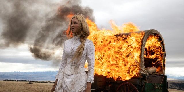Isabel May wearing a prairie dress next to a fire