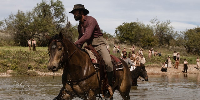 Tim McGraw riding a horse on a lake