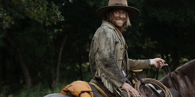 Eric Nelson wearing Western gear while riding a horse