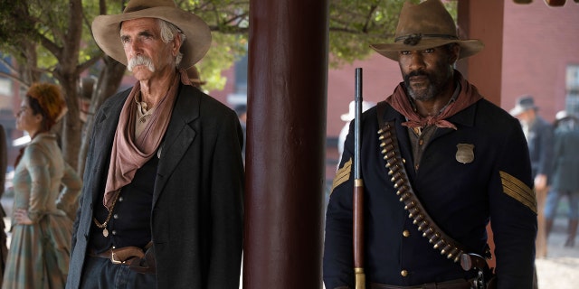 Sam Elliott and LaMonica Garrett standing next to each other outdoors in Western gear