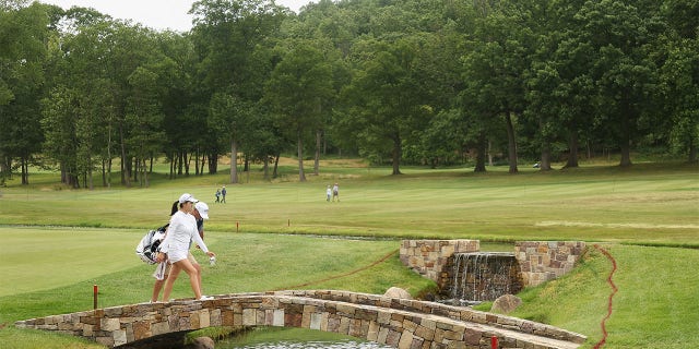 Rose Zhang walks over bridge with caddie