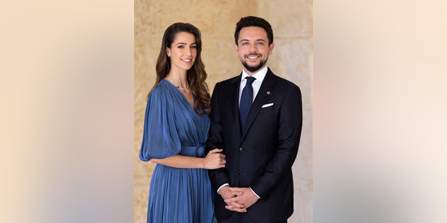Princess Rajwa wearing a blue dress next to Crown Prince Hussein in a dark suit and blue tie