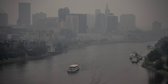 Two boats on the Mississippi River as heavy smoke blankets downtown St. Paul