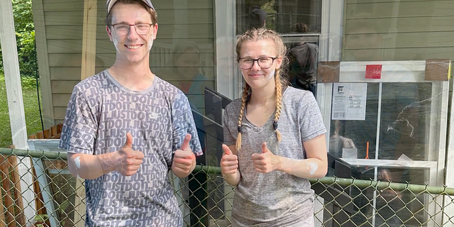 Boy and girl giving thumbs up. both have white paint spots.