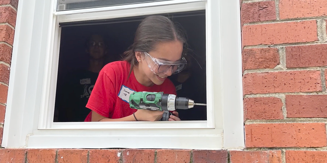 Girl with drill installing window