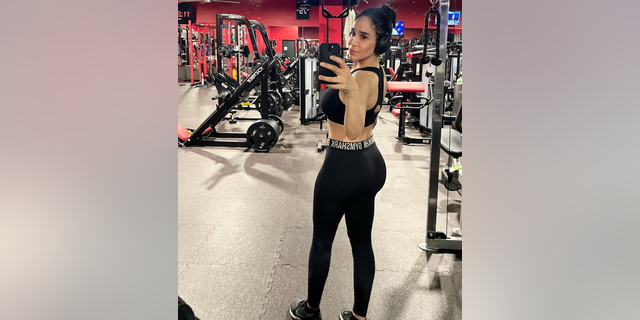 Nadya Suleman takes a picture of herself in the gym in a sports bra and leggings as she looks back at the mirror