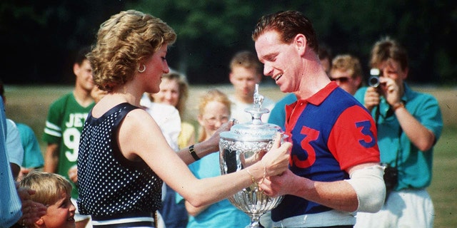 Princess Diana in a sleeveless black polka dot blouse and white pants handing a polo prize to James Hewitt