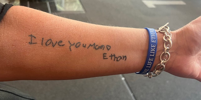 Una lectura de tatuaje en el antebrazo. "Te quiero, mamá."