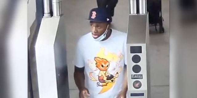 Slashing suspect wears Boston Red Sox hat and white Graphic T standing at NYC subway turnstile