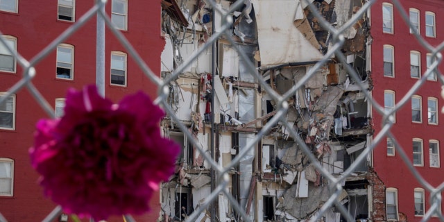 A flower hangs where on Sunday an apartment building partially collapsed in Davenport