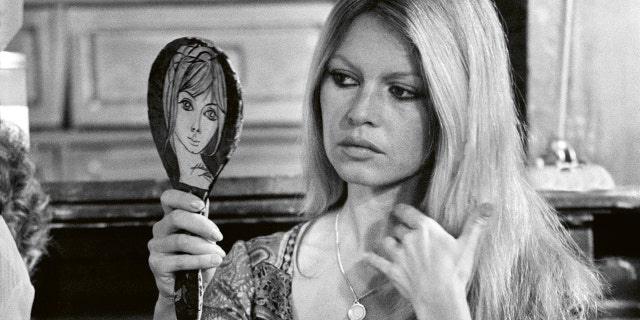 Brigitte Bardot looking somber at a mirror