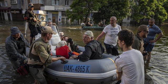 Soldados ucranianos rescatan a personas en botes tras el colapso de una presa