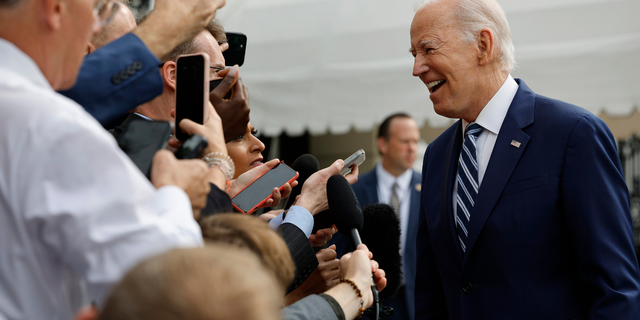 Joe Biden smiling in front of reporters