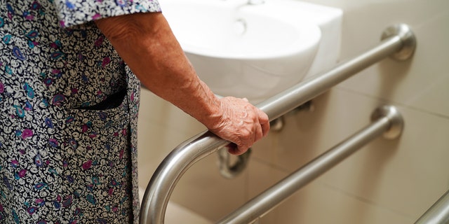 Woman holding onto handrail in bathroom 