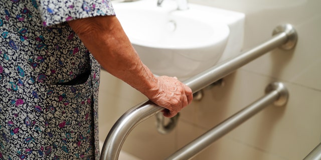 Woman holding onto handrail in bathroom 