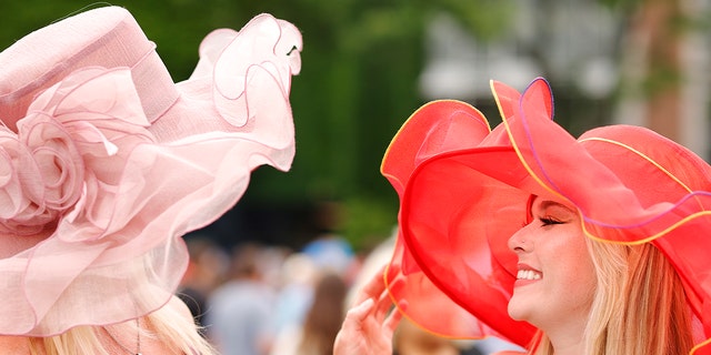 Dos espectadores con sombreros extravagantes y coloridos para Belmont Stakes