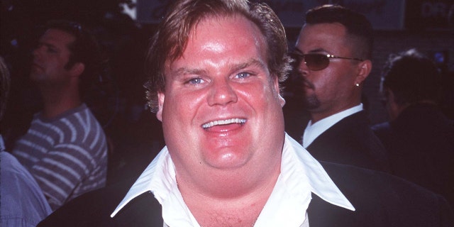 Chris Farley smiles while walking red carpet