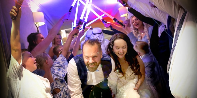 Wedding guests use lightsabers to escort out bride and groom