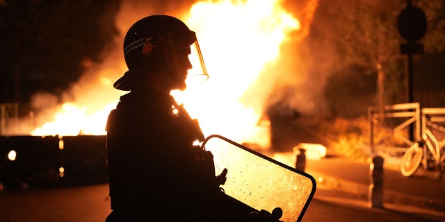 A firefighter looks on as vehicles burn following riots in Nanterre, west of Paris