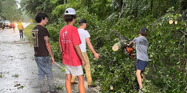 teens helping remove tree from road
