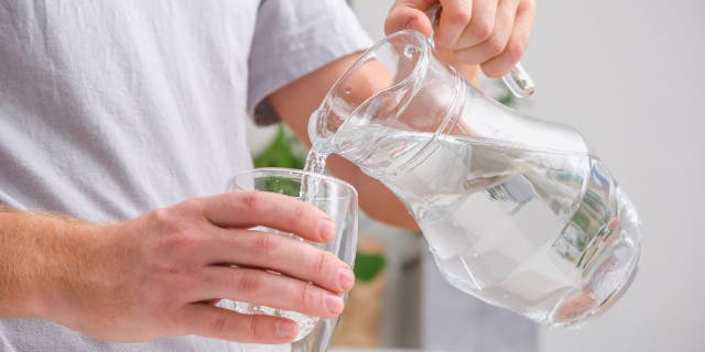 A man pours cold water into a glass.