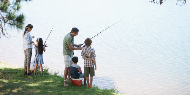Family of five goes fishing by lakeside.