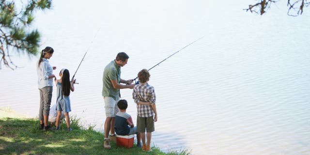 Family of five goes fishing by lakeside.