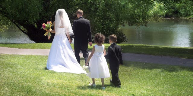 A flower girl and ring bearer follow a bride and groom.