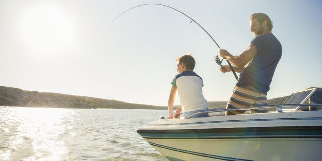 Father and son go fishing on a boat.