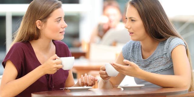 Two women have a serious conversation while sitting in a restaurant.