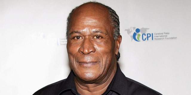 John Amos wears black shirt on red carpet at annual event.