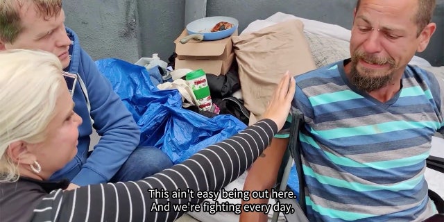 Activists speak with homeless man on San Diego sidewalk