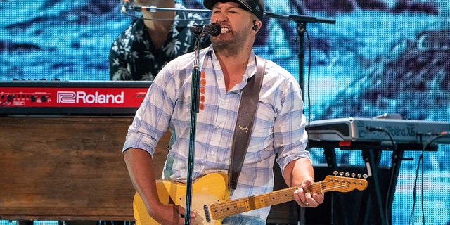 Luke Bryan plays the guitar on stage