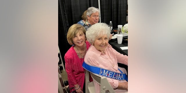 Two Women at a table, one is melba one is Drew Dillard, a man is in the background