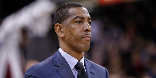     Kevin Ollie looks at the court