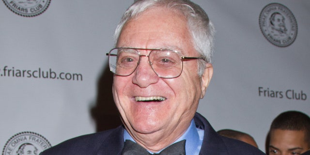 Pat Cooper wears a blue suit and bow tie on the Friars Club red carpet.