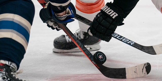 Players fighting for puck on hockey rink