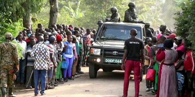 Las fuerzas de seguridad de Uganda pasan frente a una multitud tras un ataque a una escuela