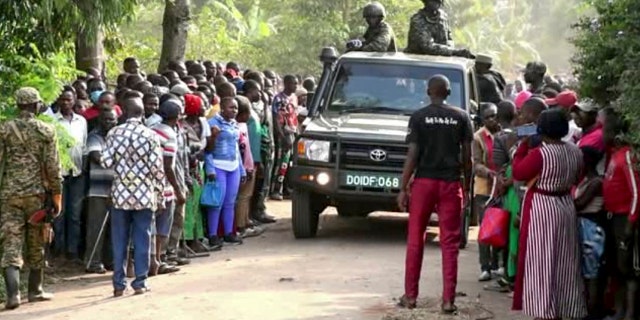 Uganda security forces drive past a crowd of people following school attack