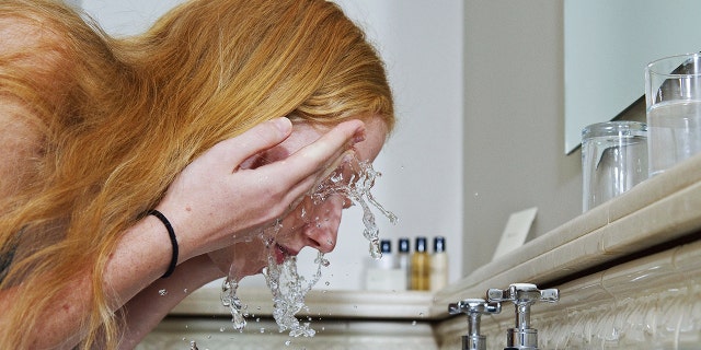A woman washing her face in the sink