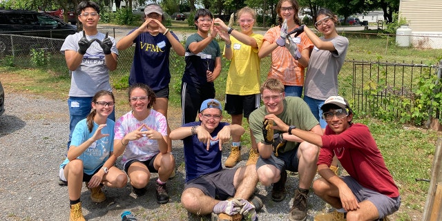 Group of teens spelling "WorkCamp" with their hands