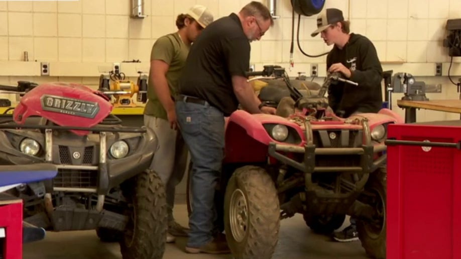 Teacher and students fixing a vehicle