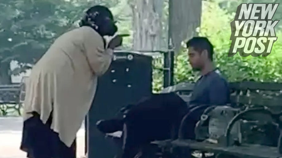 Woman gestures at man seated on park bench