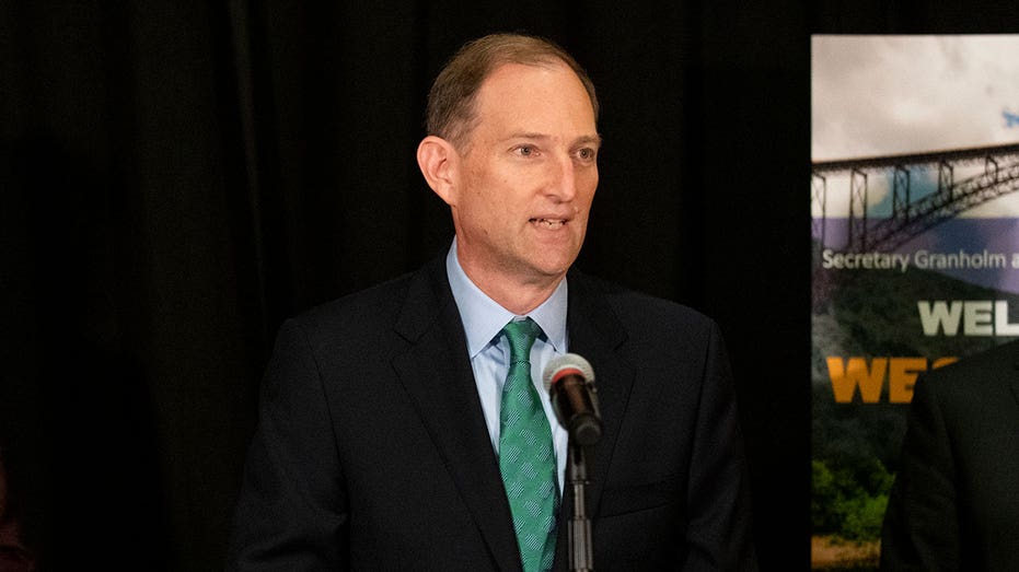 Robert Blue wears suit and green tie at podium