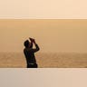 A man takes a photo of the sky.